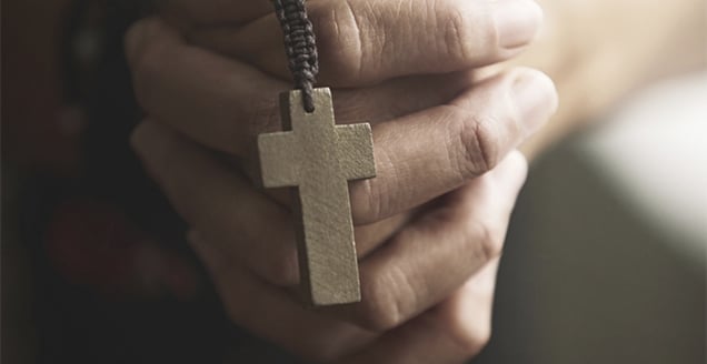 Hands holding prayer beads with crucifix