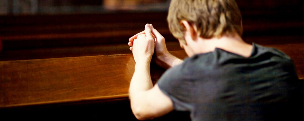 Man in prayer on church pews