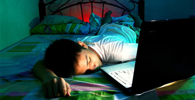 Teenager asleep in front of laptop