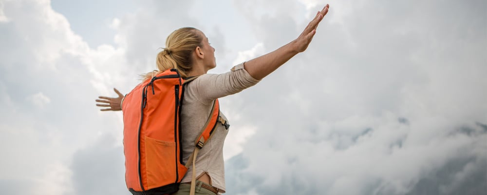 Female hiker with arms raised in the air