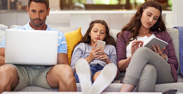 Family on couch all looking at different screens