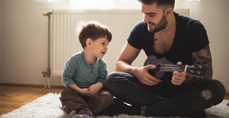 Dad playing ukelele with his son