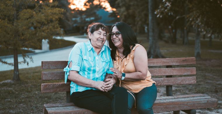 Two women laughing on park bench