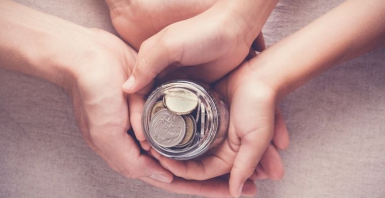 Child's and parent's hands with jar of coins