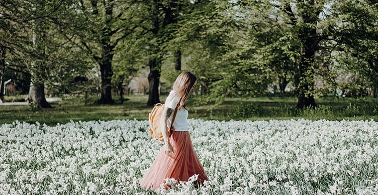 Woman walking in field of flowers