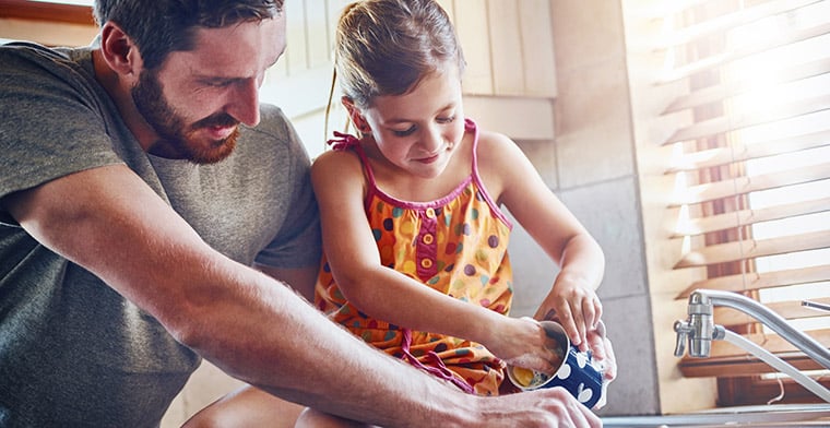 Father washing dishes with daughter