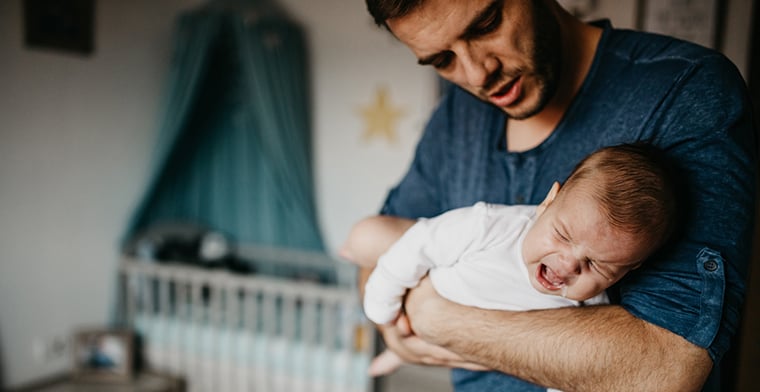 Dad Holding crying baby in the colic carry