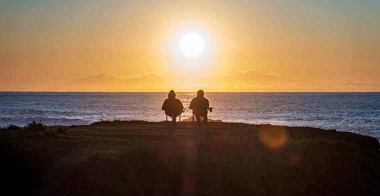 Two people watching Sunset over ocean