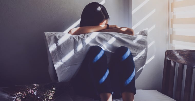 Young girl hiding face in pillow