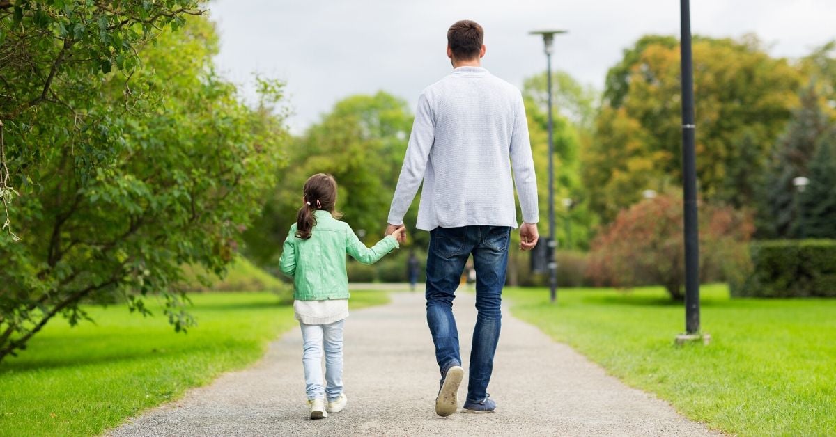 Dad walking with daughter in park -