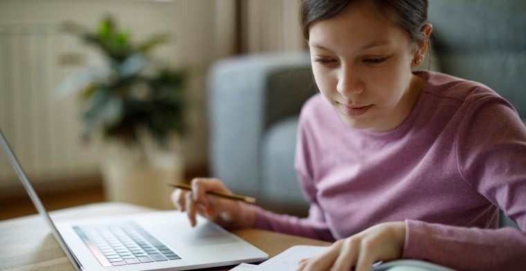 Teenage girl using laptop for studying at home