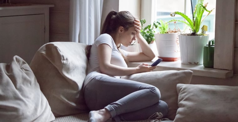 Young woman on phone indoors sad