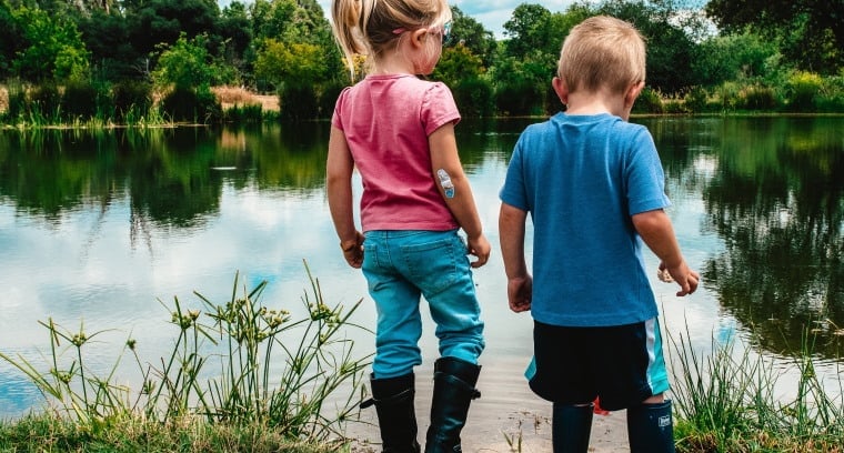 Little boy and girl by a pond by meritt-thomas