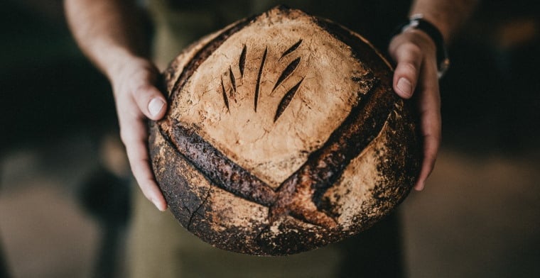 Baker holding loaf of bread nathan-dumlao