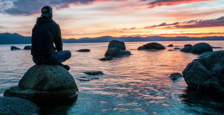 Young man watching sunrise over ocean
