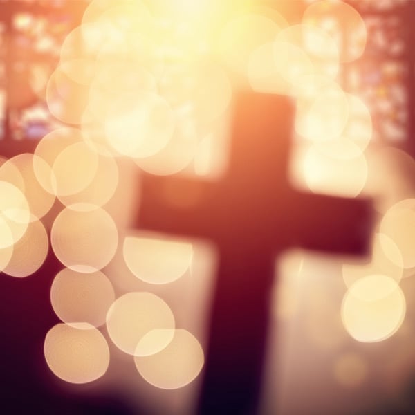 Silhouette of cross through blurry lights