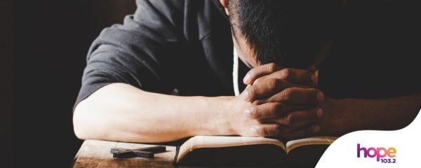 Man Praying to God over a Bible and with a cross by Canva Pro